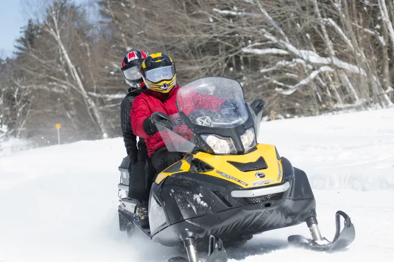 Two people ride on a snowmobile in fresh snow