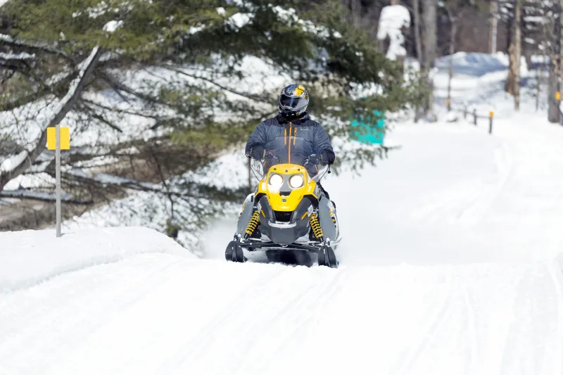 A solo snowmobiler rides on a groomed trail in winter