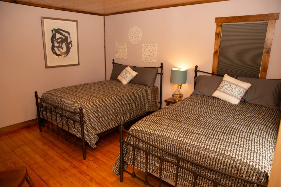 Motel room in Tupper Lake with two full beds and decor.