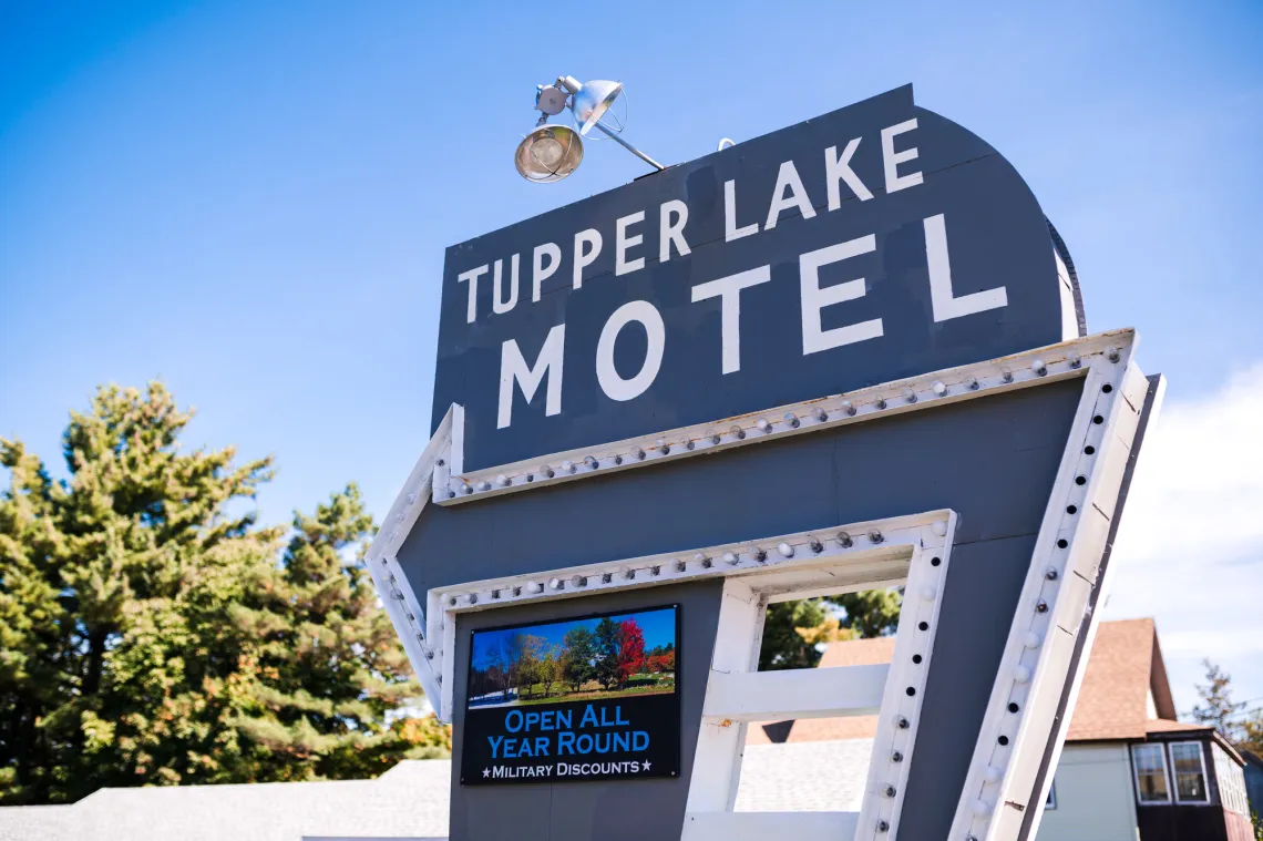 The Tupper Lake Motel Sign in front a bright blue Adirondack sky