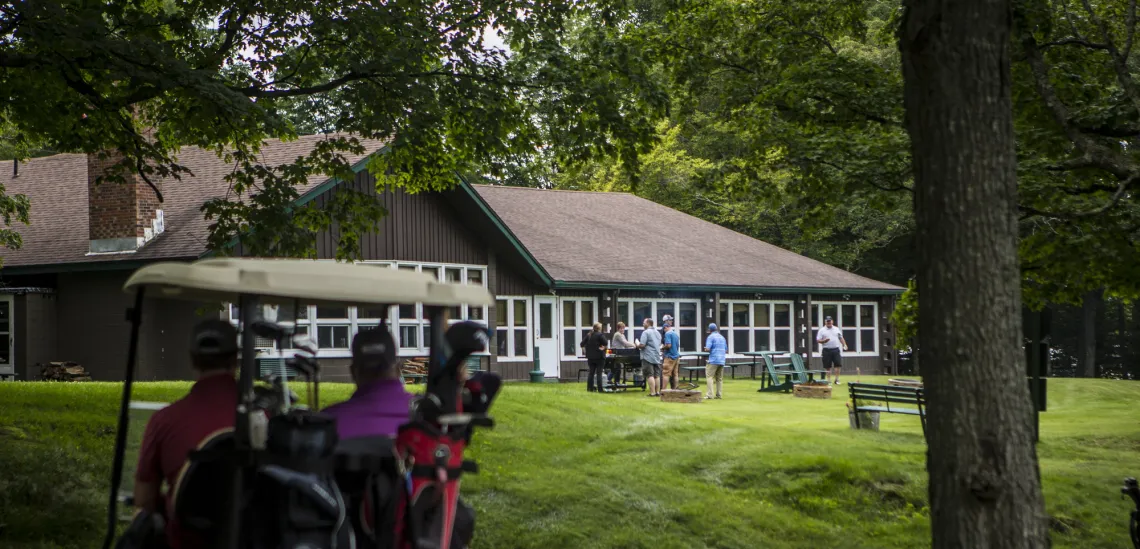 Two golfers in a cart approach the restaurant at the Tupper Lake Golf Club