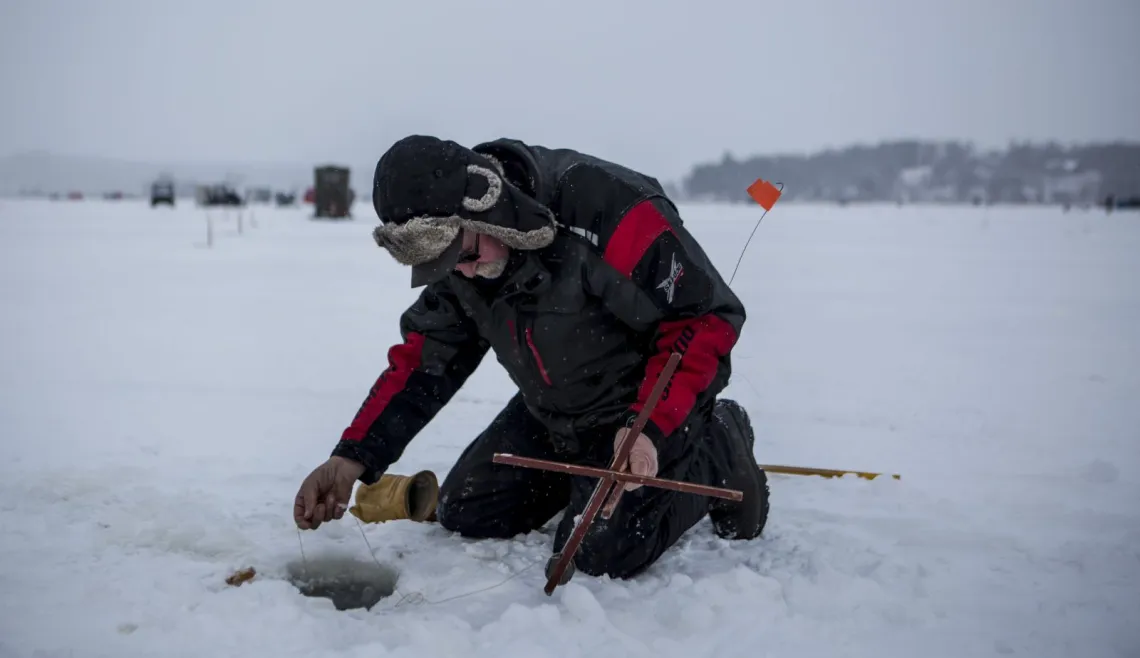 A man lowers his line into a hole in the ice