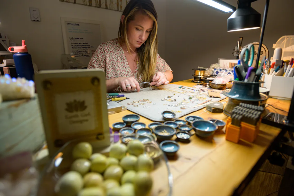 A woman works at a jewelers table.