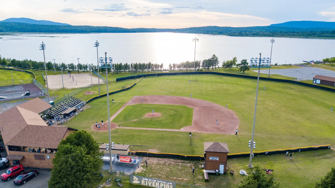 An aerial view of a baseball field with a large lake and mountains beyond.
