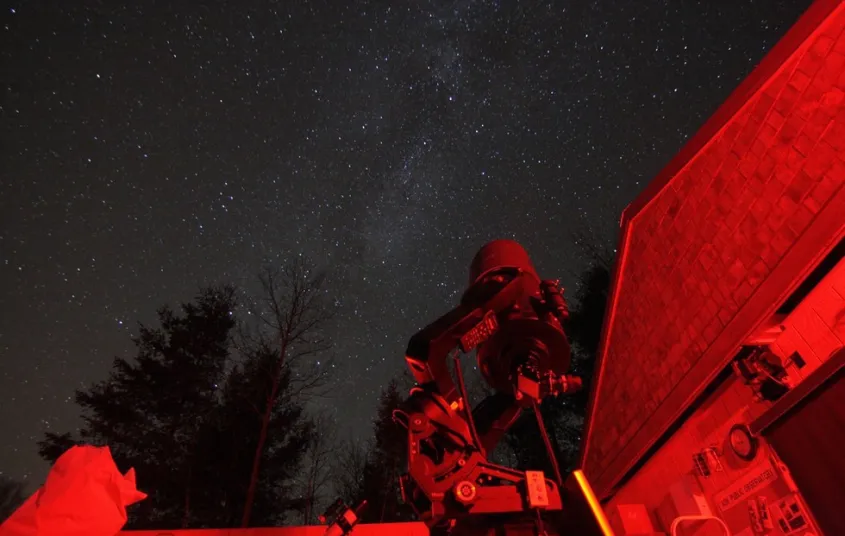 A telescope looks up at the stars&#44; glowing with red light