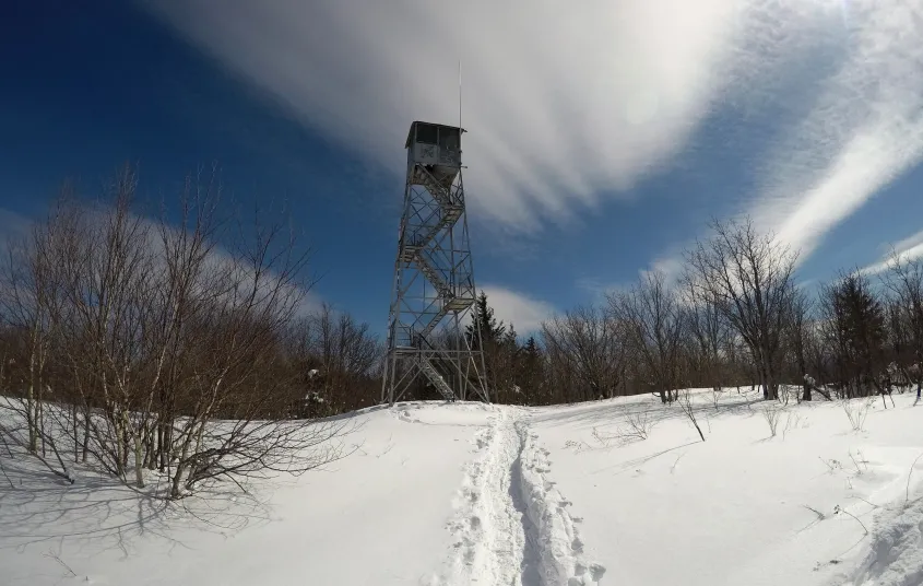 A firetower in the winter with wispy clouds above