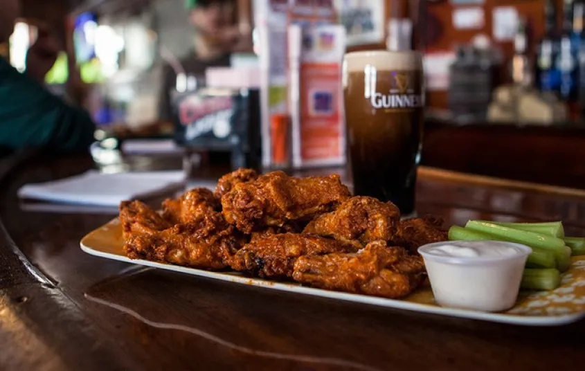 Chicken wings and guiness in a glass.