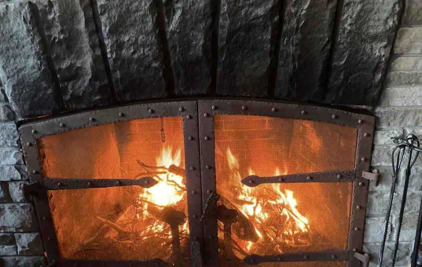 A fire burns behind the black metal grate in the stone fireplace.