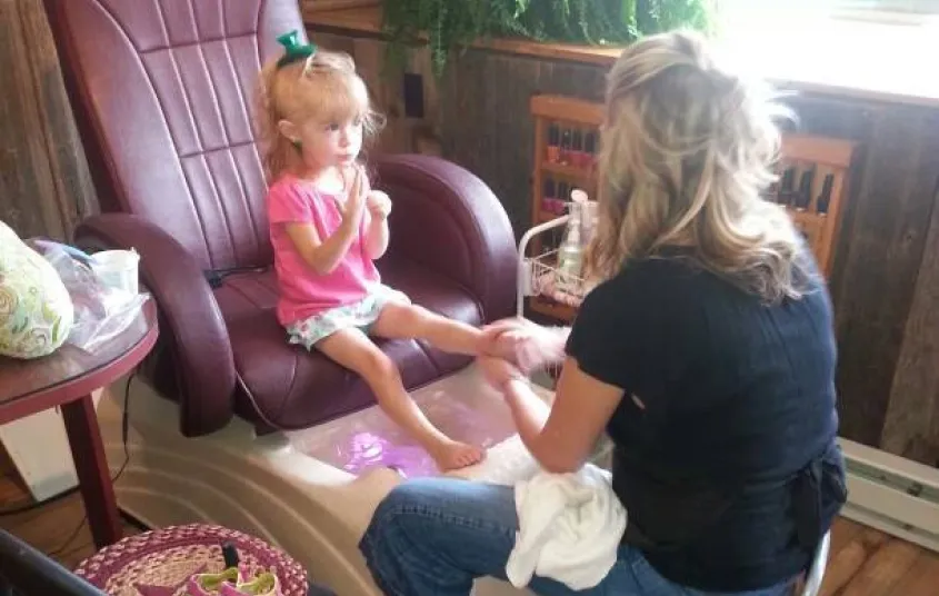 A little girl sits in a pedicure chair.