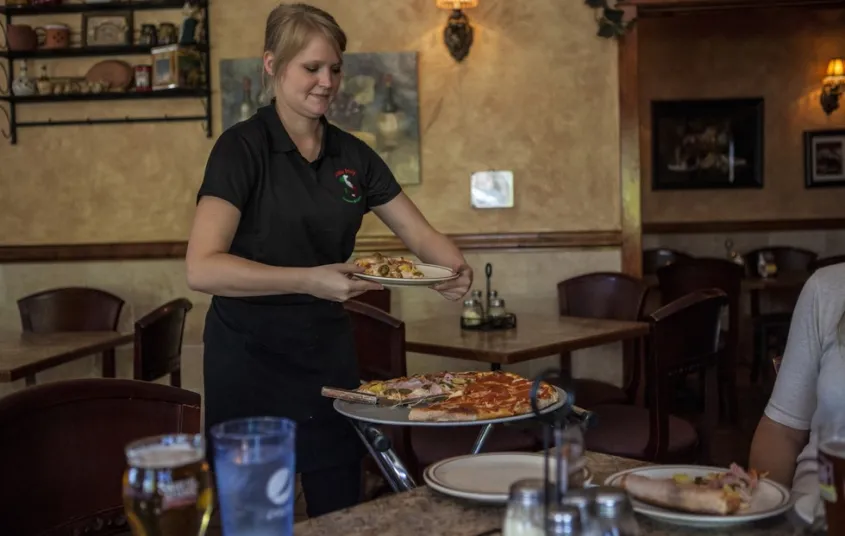 A waitress brings pizza to the table