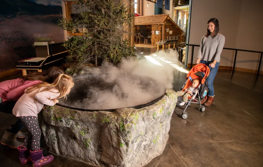 Two children play a game throwing snowballs into buckets set up on a suspended walkway on the Wild Center's Wild Walk