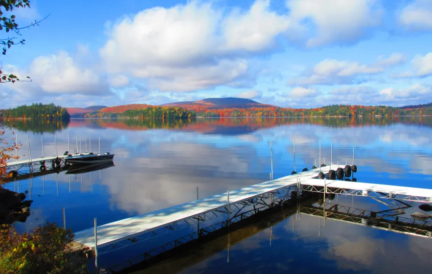 Long dock over the peaceful lake ringed in fall foliage.