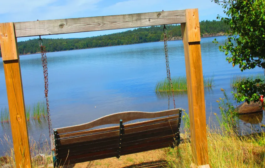 A wooden rocking bench next to the lake.