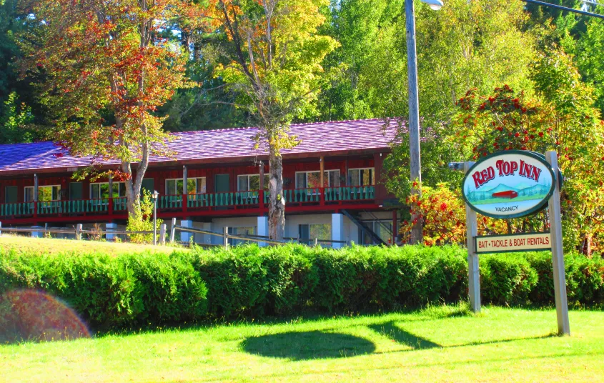 The green grass and shrubs and the red roofing of the Red Top Inn.