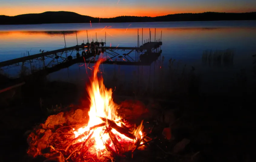 A bon fire by the lake with the red sunset.