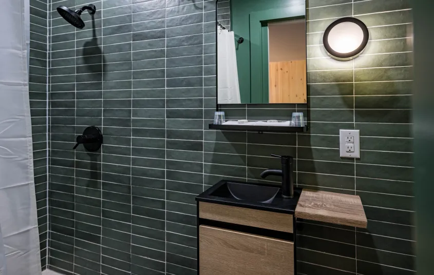 Emerald green tiles with white grout in the and dark vanity.