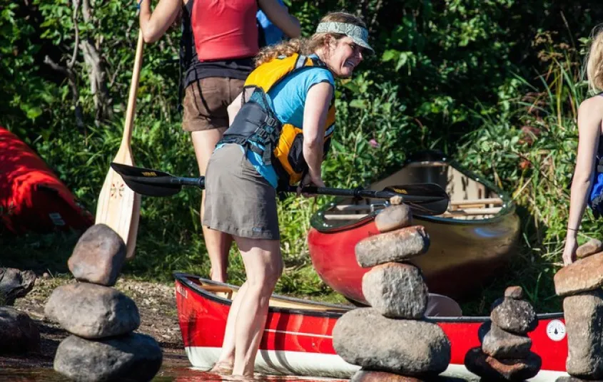 A smiling woman in a life jacket ready to board a boat.