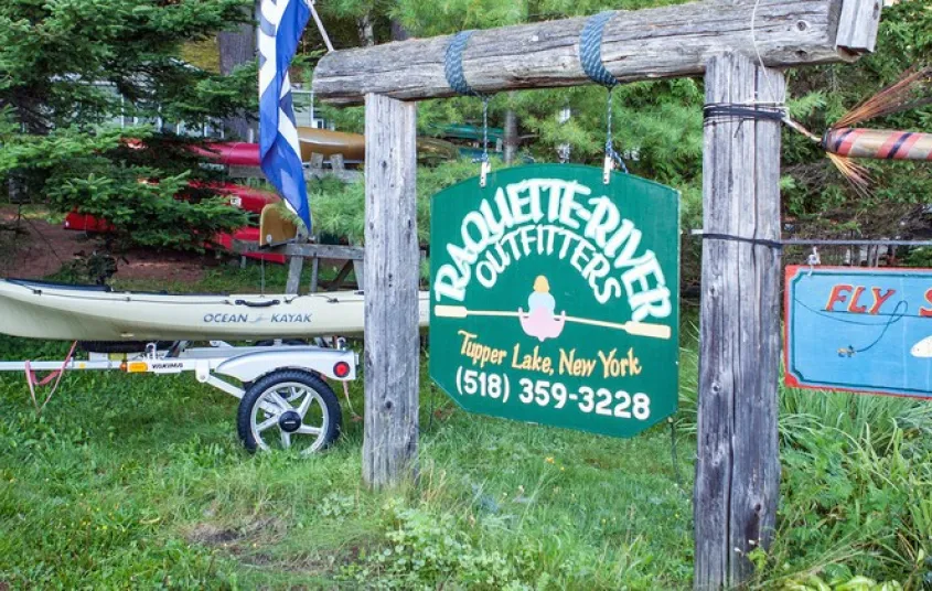 The green sign for Raquette River Outfitters