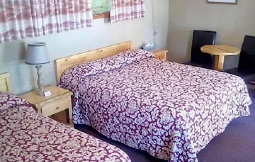 A two queen room with window and red and white bedding.