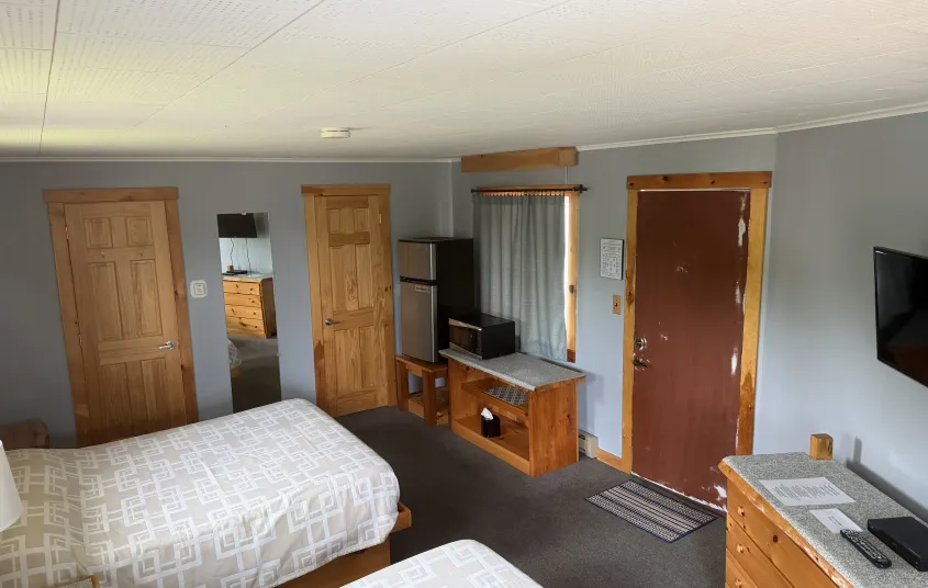 A king size bed in a room with dusty salmon walls at the Tupper Lake Motel.