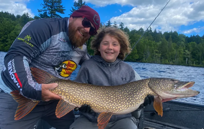 A man and a child hold a pike.