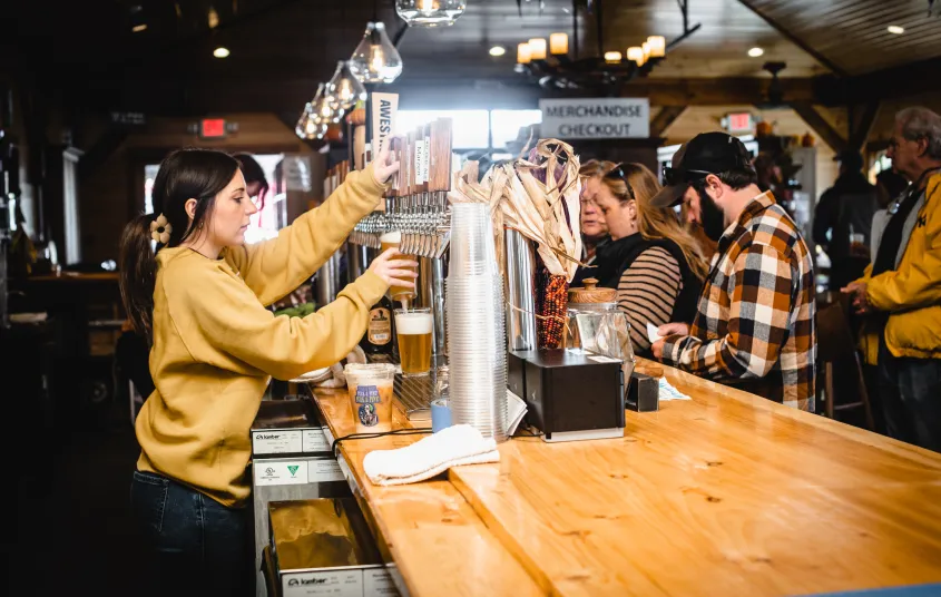 A beer is poured from the many tap handles as patrons wait on the other side of the bar