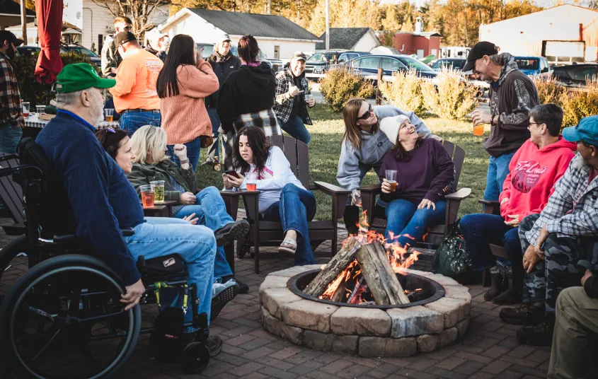 People enjoying nice weather on the accessible brick patio with fire ring.