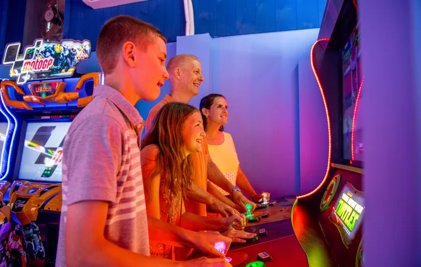 Family gathers around the arcade game.