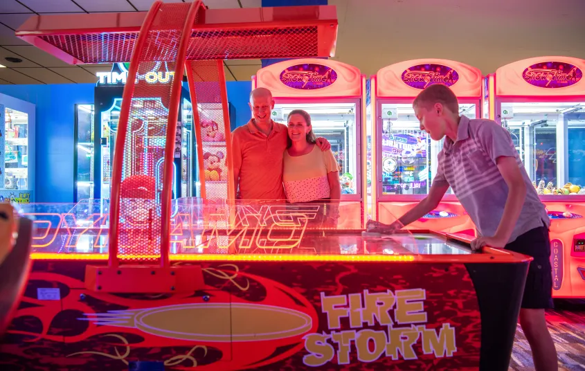 People gather around the air hockey table to watch the match.