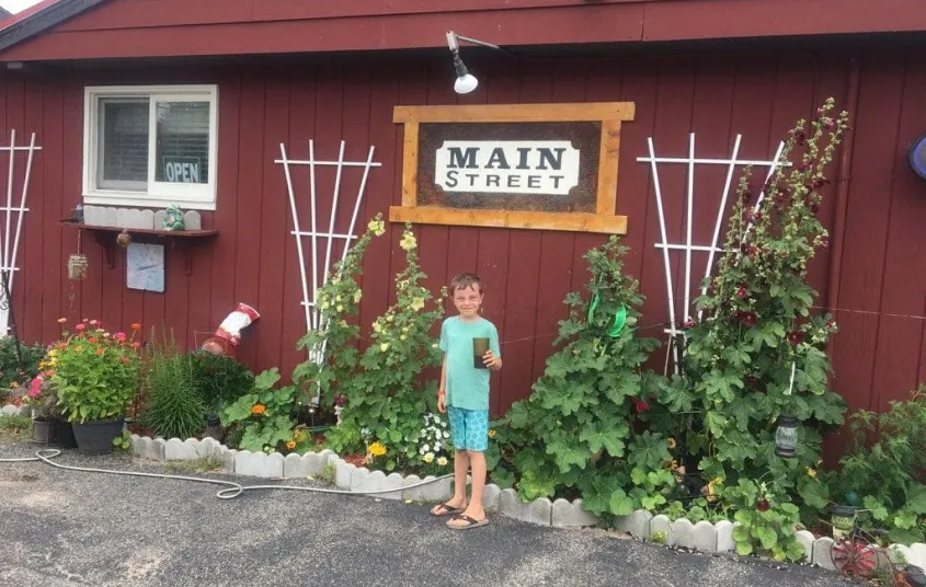 An excited child stands with mother under the Main Street Restaurant sign.