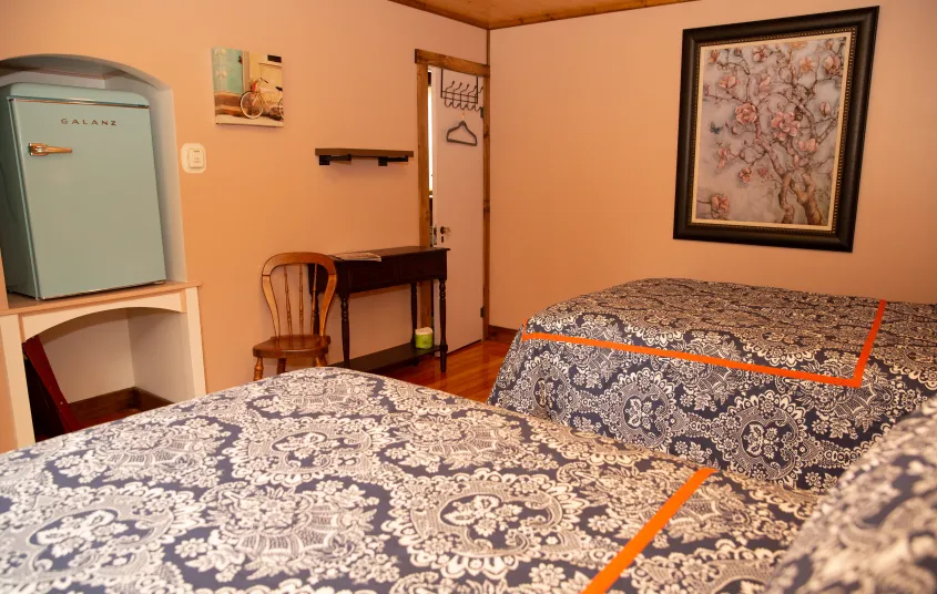 The white and blue bedding in a two queen room with small dining table.