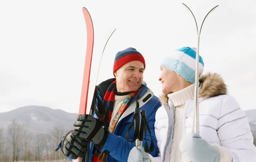 A smiling couple holding snow skis