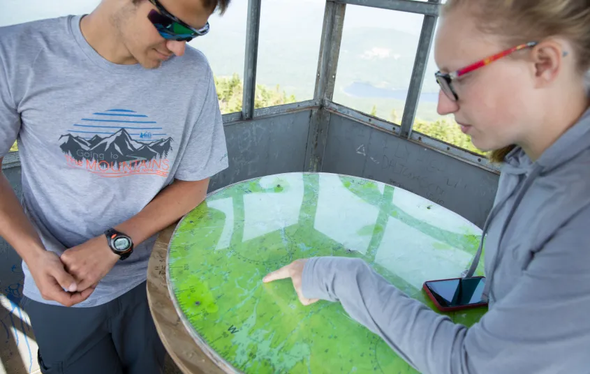 Two hikers looking at a map in a firetower cabin
