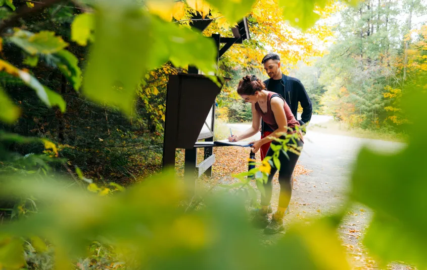 A couple signing into the Goodman Mountain trailhead register