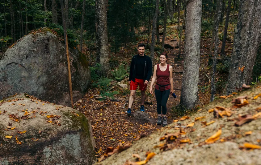 Two hikers approaching large rocks
