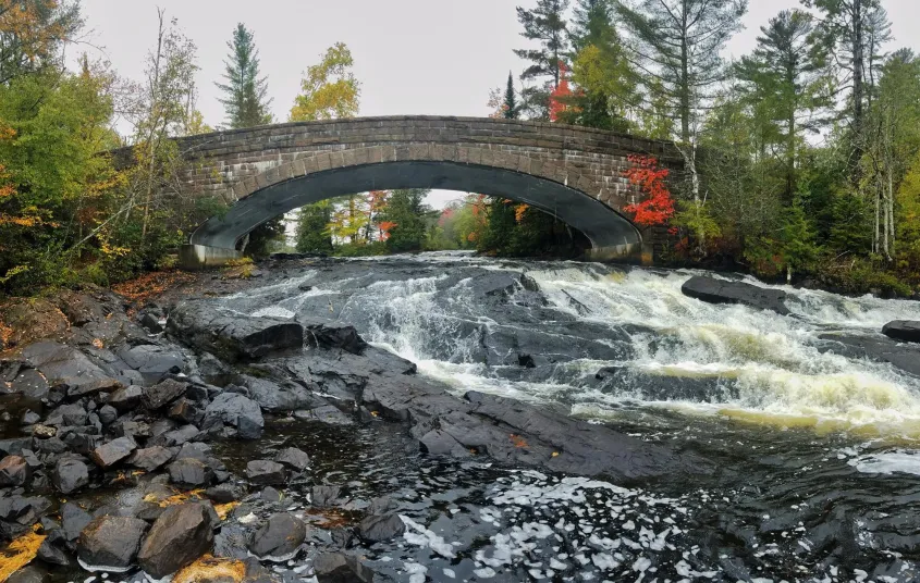The arching bridge over Bog River Falls