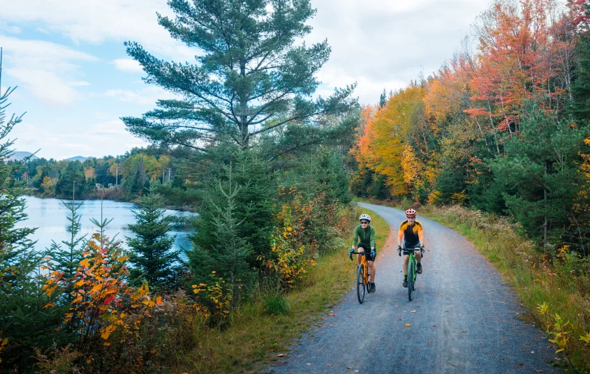 Two cyclists ride on a smooth gravel trail in fall