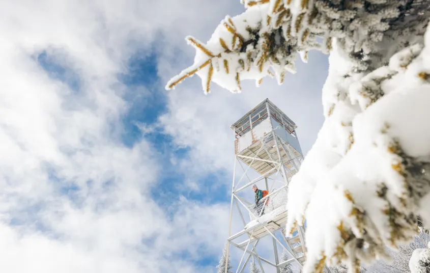 A hiker on the wintry firetower of Owls Head Mountain