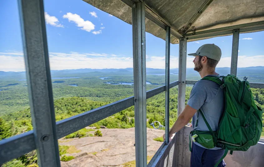 A hiker standing in the firetower cab of St Regis Mountain
