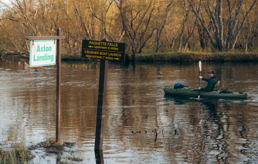 A kayaker going by a sign for Axton Landing
