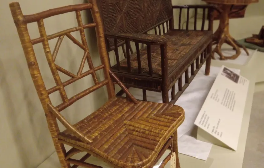  a large sign with the name and a massive wooden chair by the sidewalk