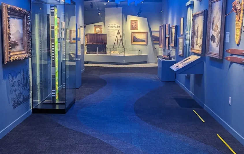 Art pieces on display in a long hallway with blue walls