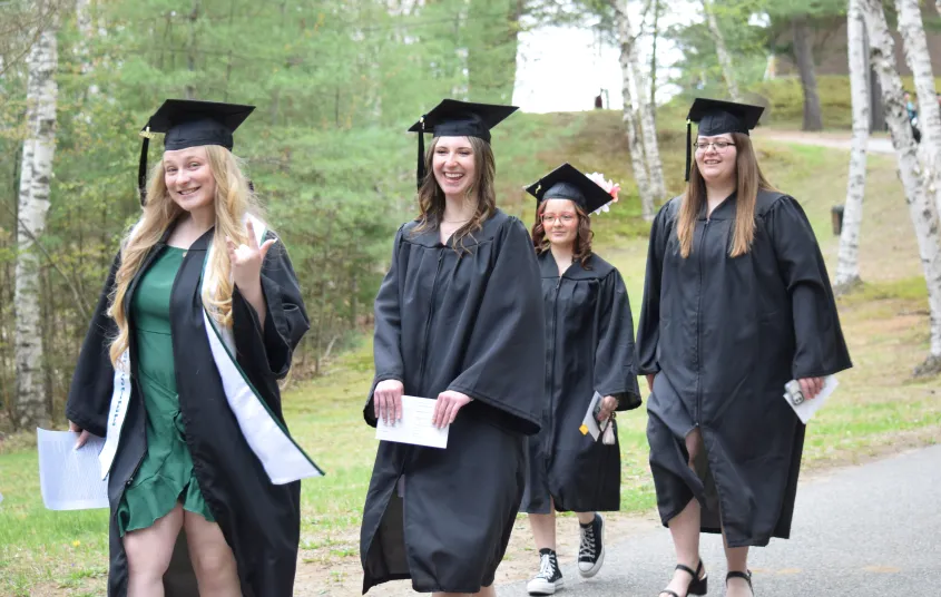 Smiling graduates walk by.