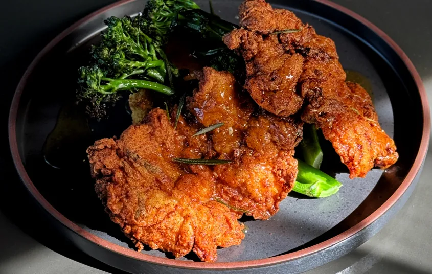 Beautifully fried and seasoned chicken plated with broccolini