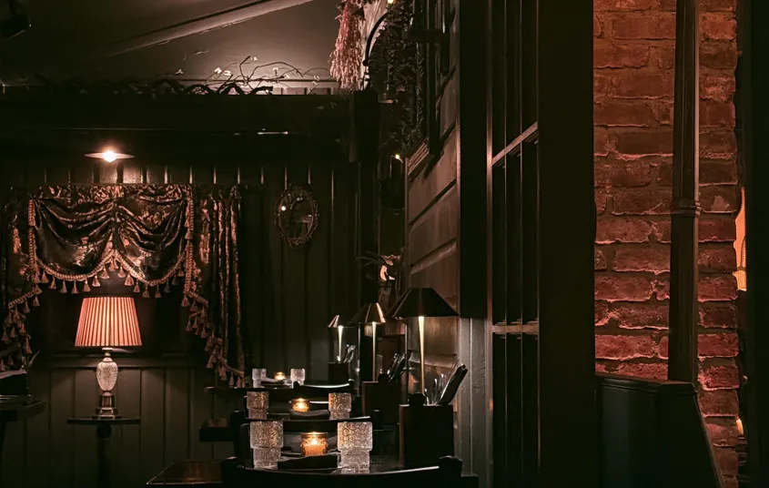 The dark and moody seating area with crystal glasses and warm lighting.