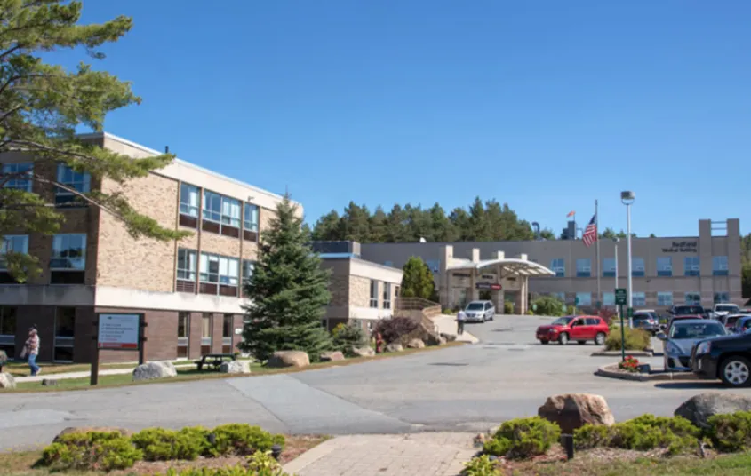 The big brick building and parking area of Adirondack Health Saranac Lake.