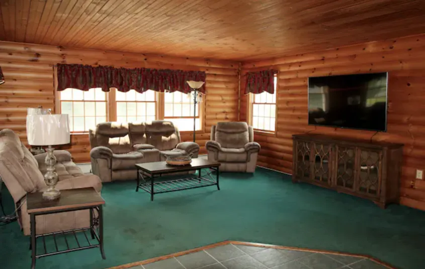 A great room with green carpet and wood paneled walls.