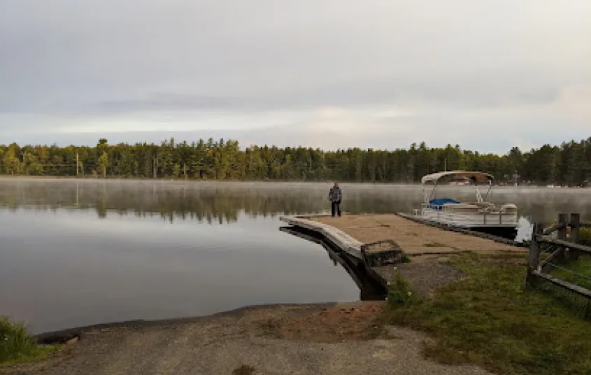 Sturdy boat launch onto a picturesque lake as smooth as glass and ringed with pines