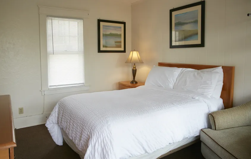 Plush white linens on a king bed in a bright room at The Ashley.