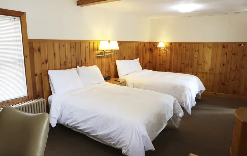 Plush white linens on two queen beds at The Ashley.